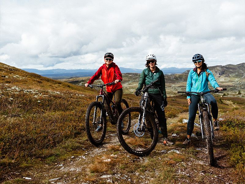 tre damer som er på hver sin sykkel og smiler