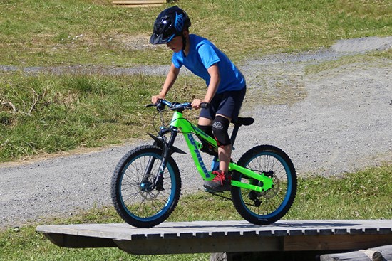 Smilende gutt med sykkehjelm som holder i rattet på sykkelen