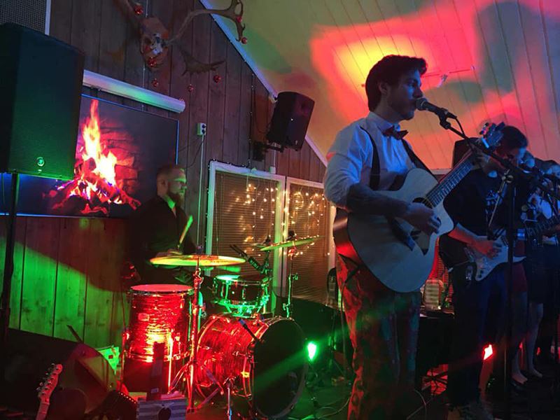 Familien Lopes inviterer til sin 4. årlige julekonsert på Segalstad seter. Band på scenen med lys i grønt og rødt. God stemning.