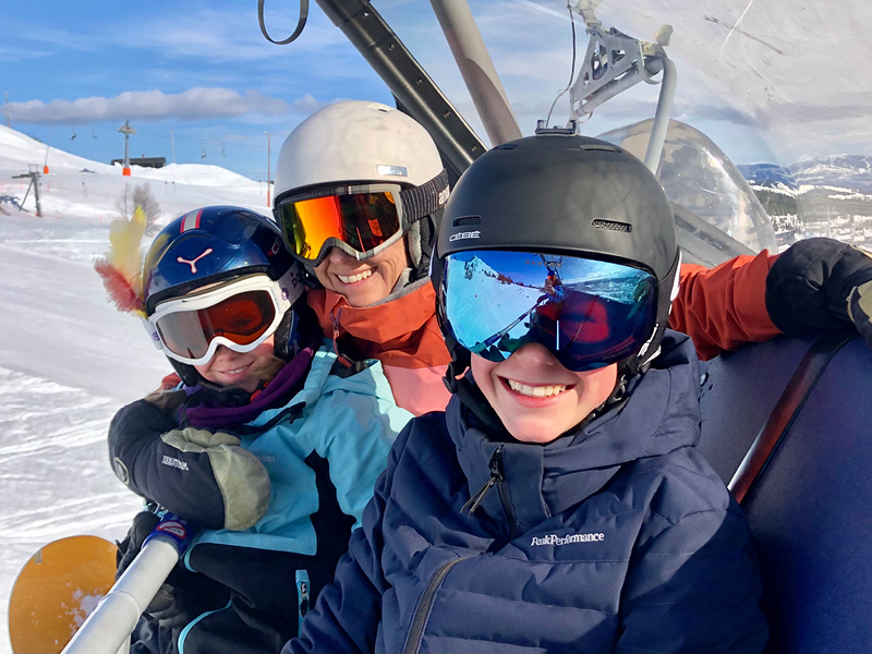 En voksen og to barn med skibriller i stolheis