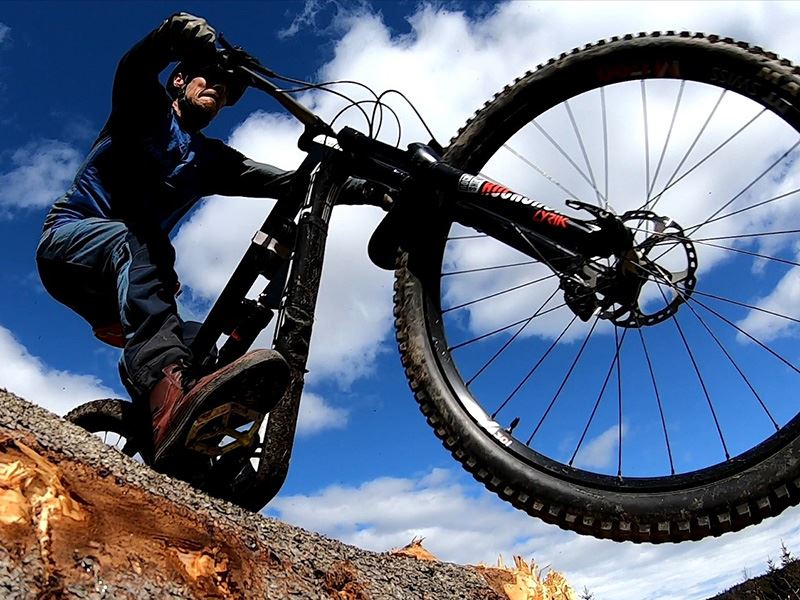 dame i blå jakke som sitter på steiner med sykkel ved siden av seg