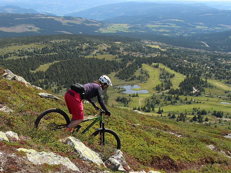 smilende dame med rød jakke, sykkelhjelm og sykkel