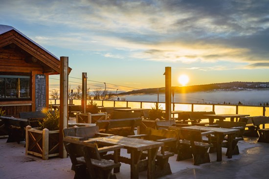 Bilde av Nystua på Skeikampen. Rødt hus midt i skibakken. Snø og blå himmel. 